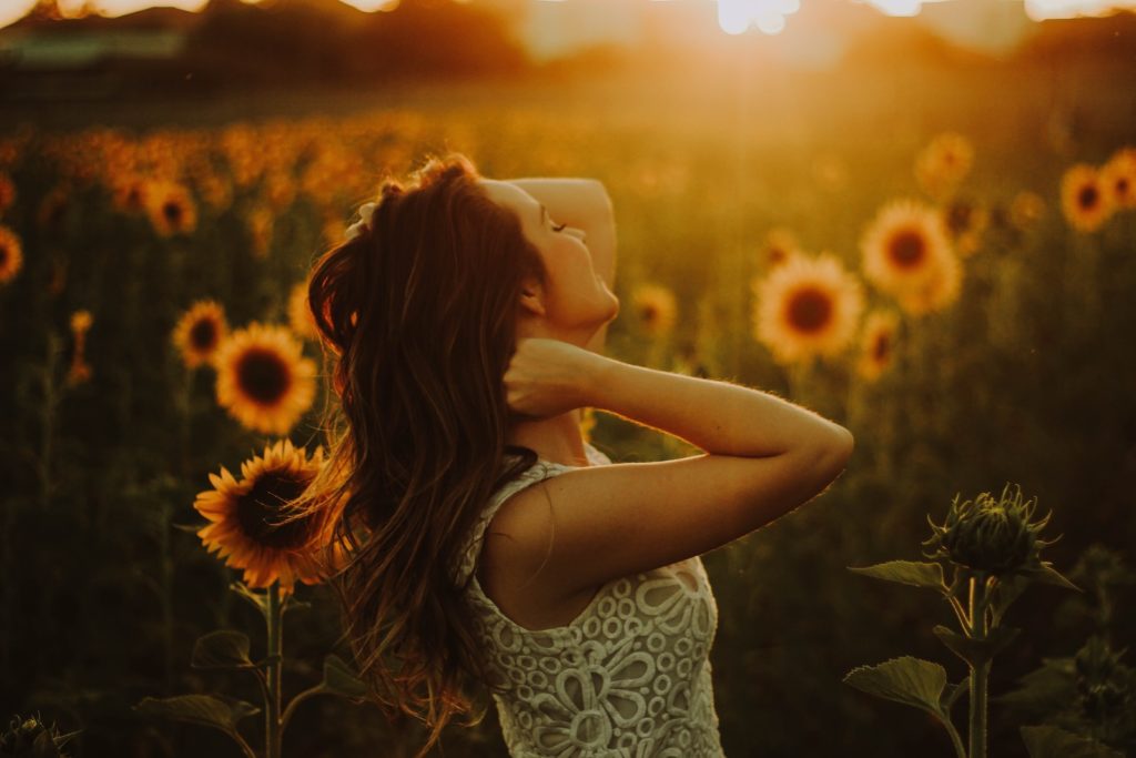 A woman standing near sunflower field. Photo by Rodolfo Sanches Carvalho.