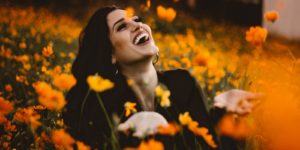 A woman laughing on flower field.Photo by Allef Vinicius