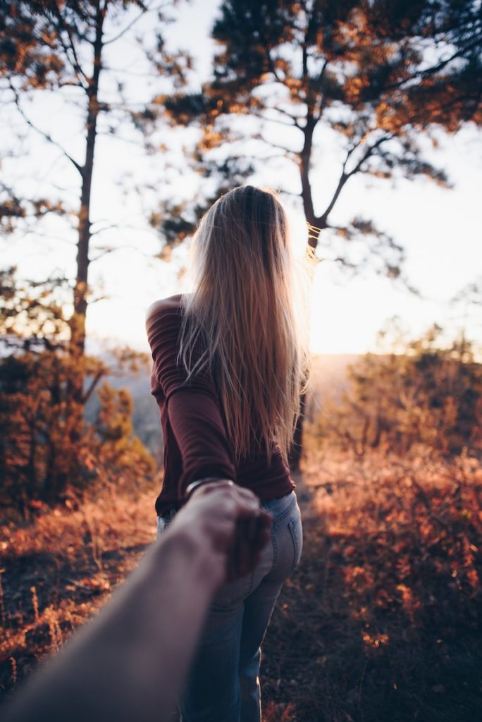 A woman holding someone's hand while walking through a romantic fall afternoon.Photo by Nathan McBride