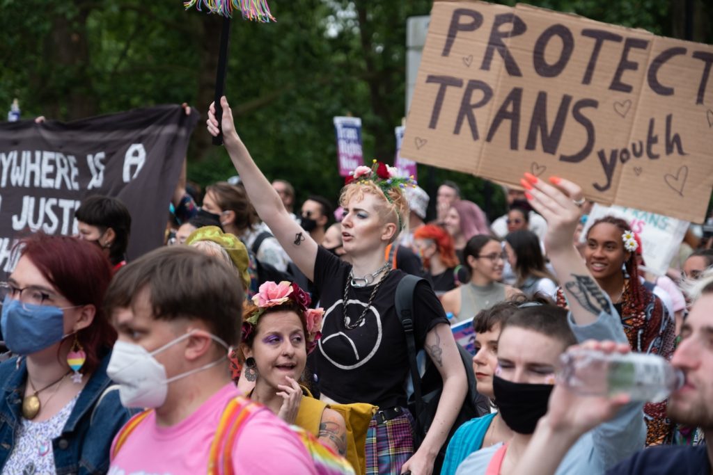 A crowd of people with face masks and signs for a protect trans youth rally .Photo by Ehimetalor Akhere Unuabona